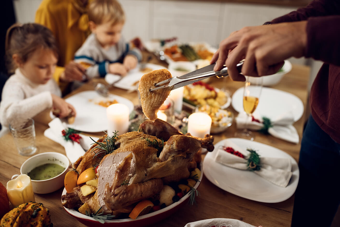 close-up-of-man-serving-turkey-meat-during-family